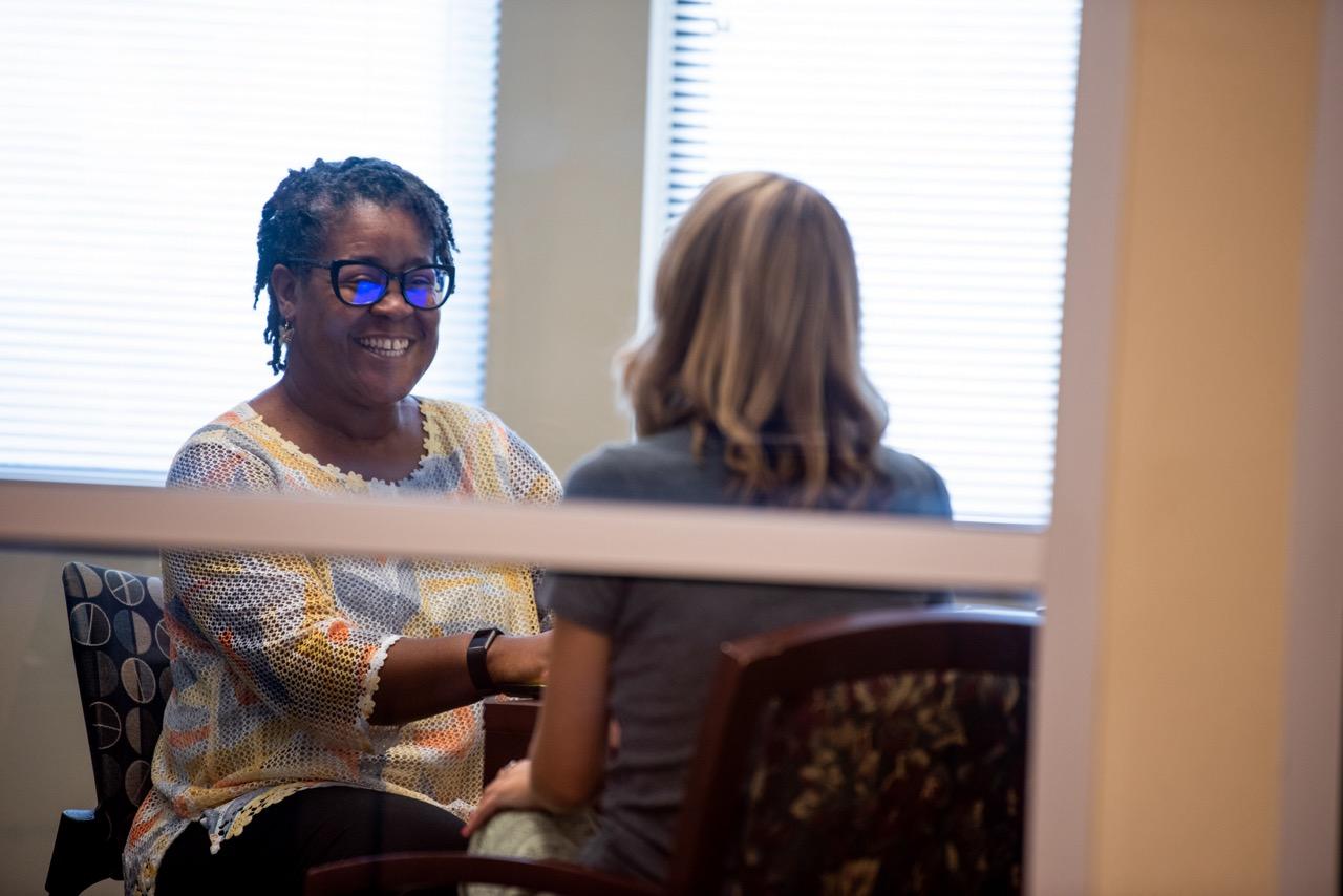 A female College employee is talking to a female student in an office.