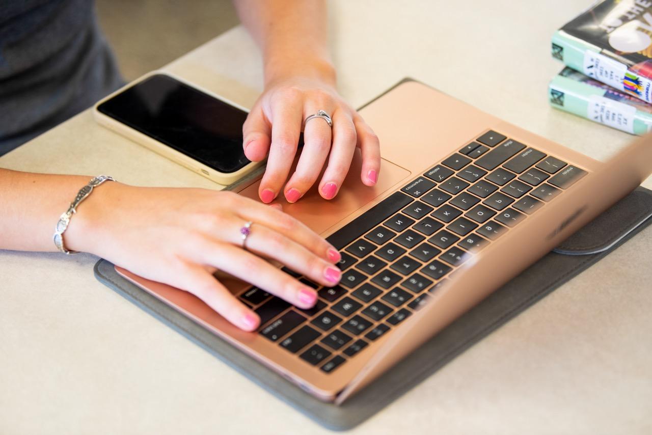 A woman's hands typing on a laptop