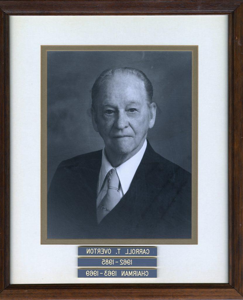 Framed black and white portrait of an older man with three engraved nameplates below.